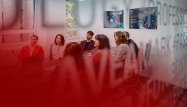 Group of professionals seated around a conference table in a glass-walled room, laptops open and screens displaying data as they discuss.