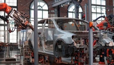 Industrial robot arms in an automotive plant assembling a car body on a production line.